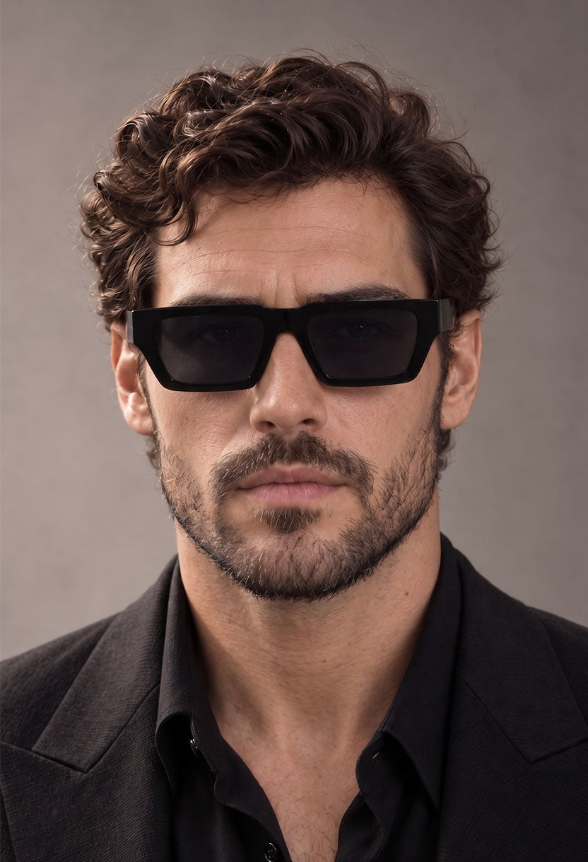 Man in a black shirt and blazer wearing NEW STATEMENT NEXUS sunglasses in black, front view #color_black
