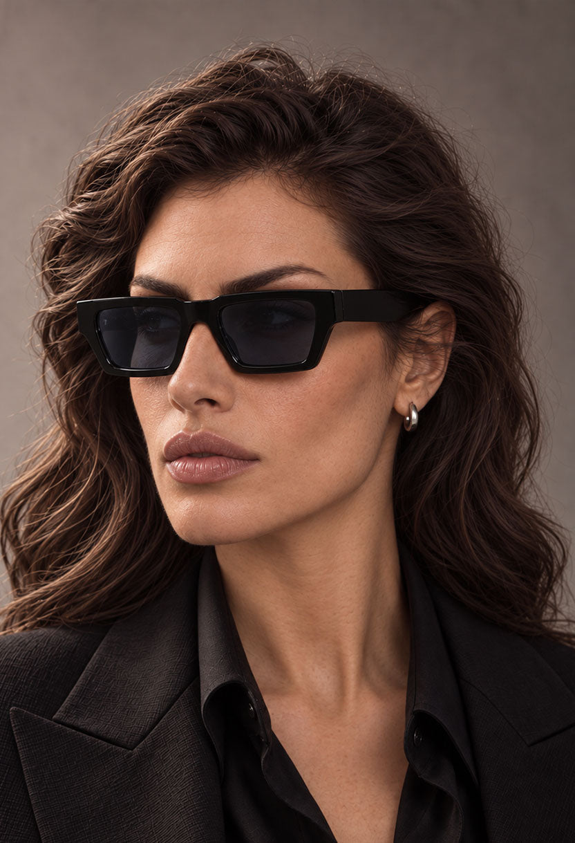Woman in a black blazer wearing NEW STATEMENT NEXUS sunglasses in black, side angle #color_black