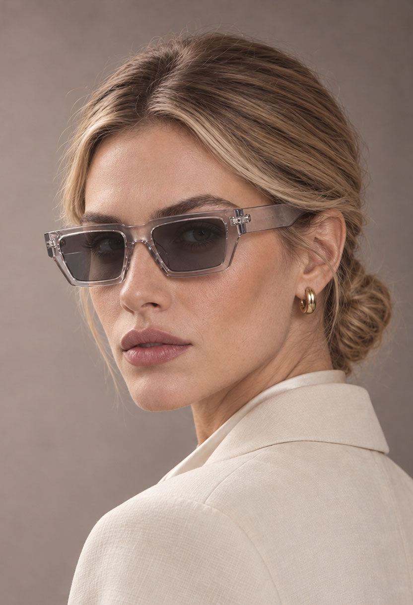 Blonde woman wearing NEW STATEMENT NEXUS sunglasses in transparent, turned to show the squared frame #color_transparant